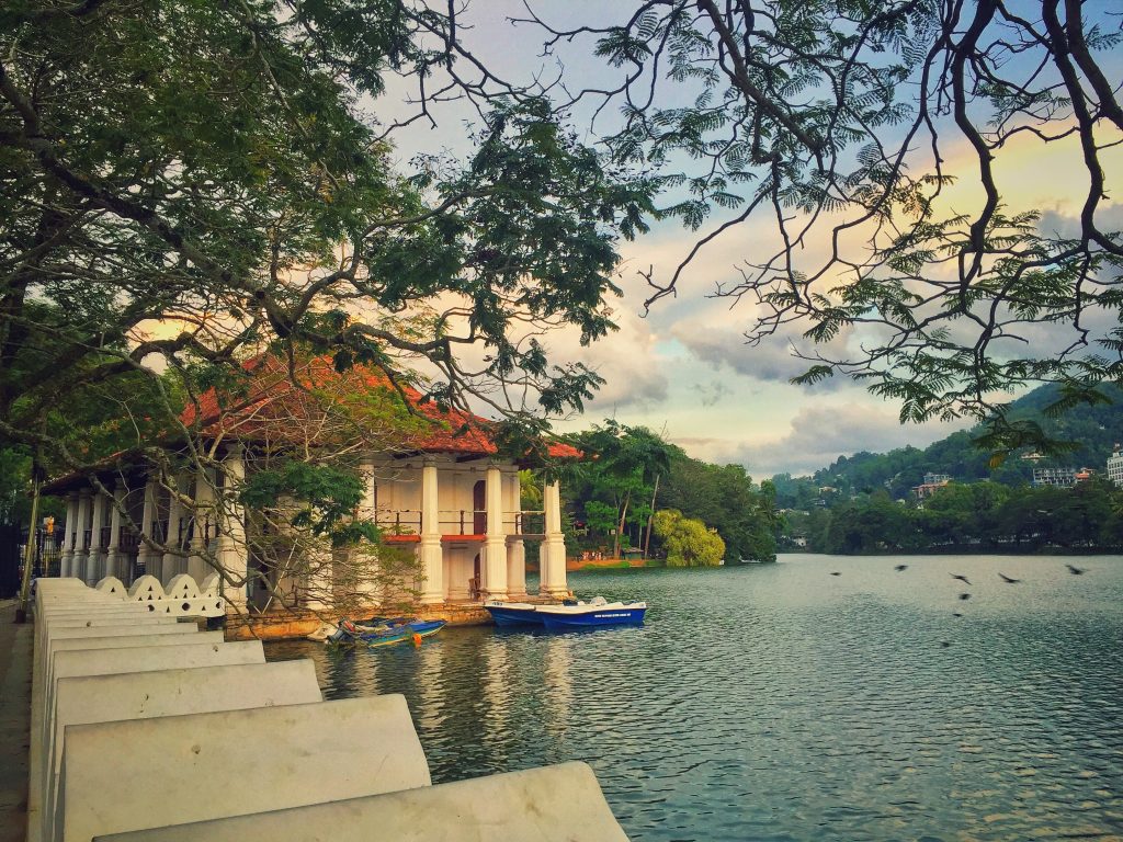 white and brown concrete building near body of water in kandy lake during daytime