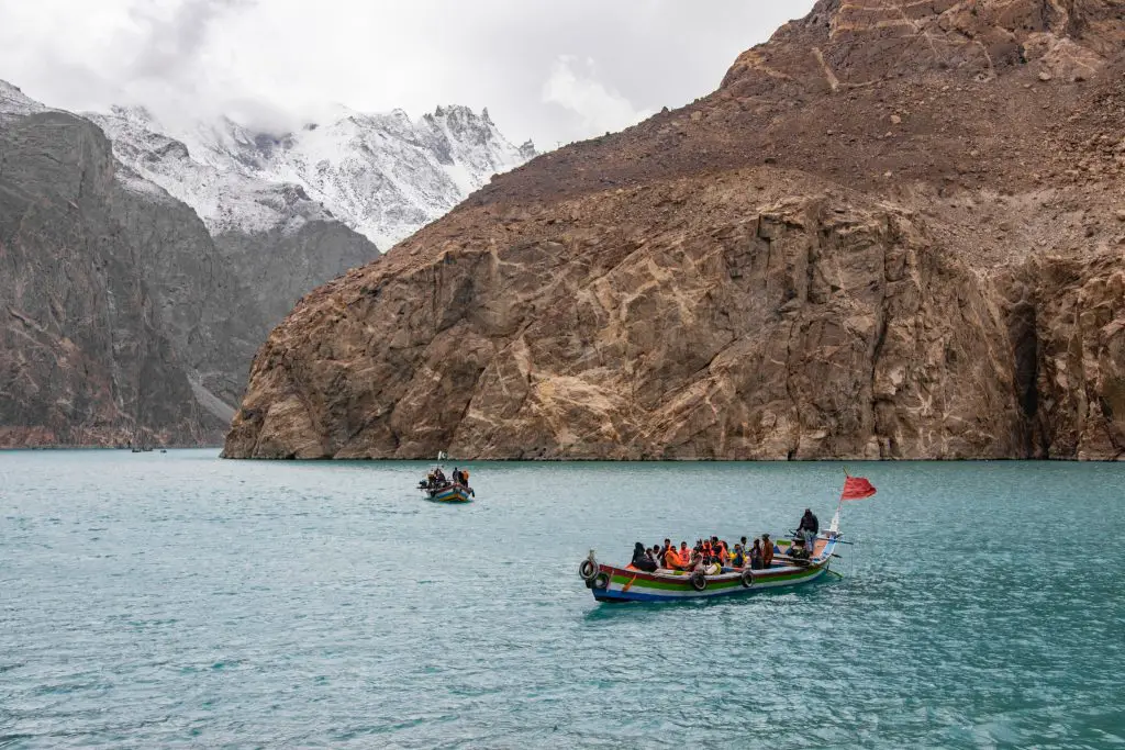 people riding on boat on sea near mountain during daytime