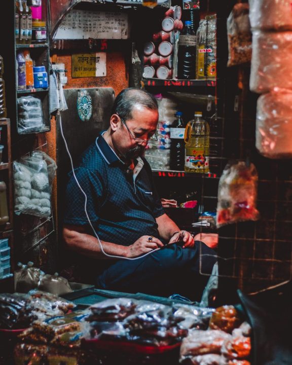 man in blue polo shirt sitting inside brown room- Thamel market
