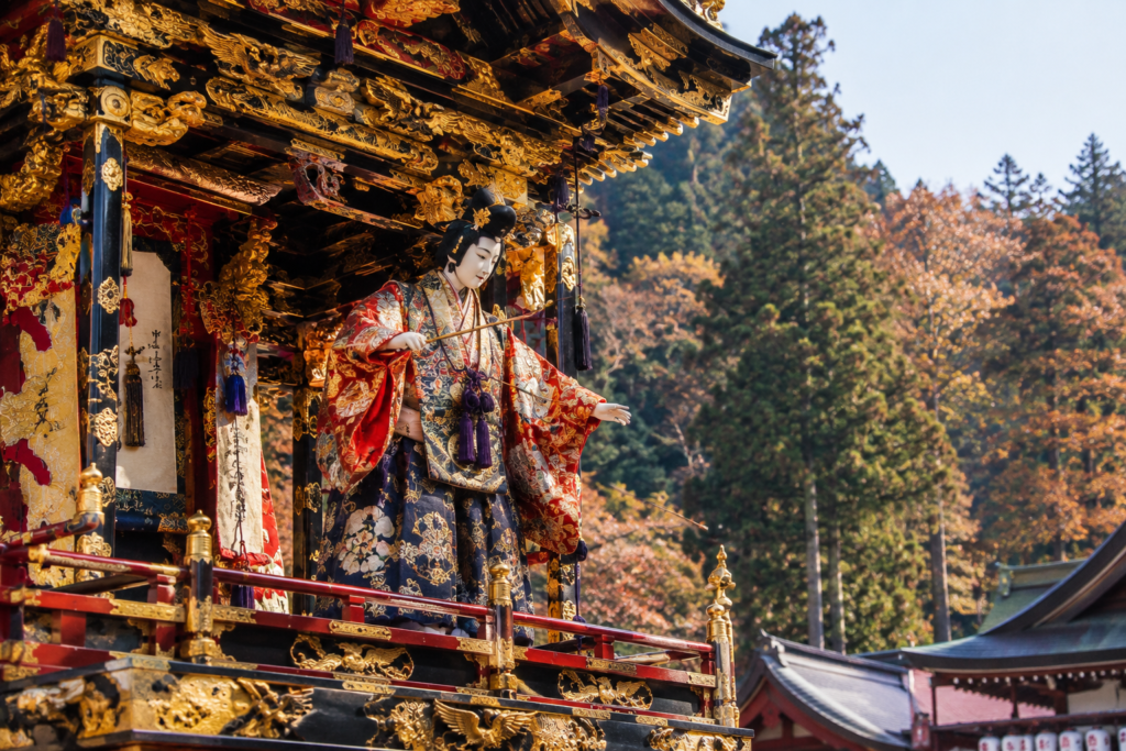 ntricate mechanical wooden karakuri puppet performing acrobatic stunts atop a gilded festival float at Sakurayama Hachiman Shrine