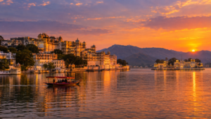 Golden hour sunset over Lake Pichola with the illuminated City Palace and white Taj Lake Palace in Udaipur Rajasthan