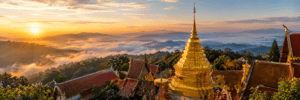 Golden chedi spire of Wat Phra That Doi Suthep rising above misty green mountain forests in Chiang Mai