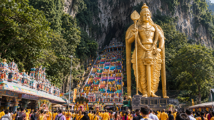 Golden Lord Murugan statue and steep colorful 272 steps crowded with devotees during Thaipusam at Batu Caves