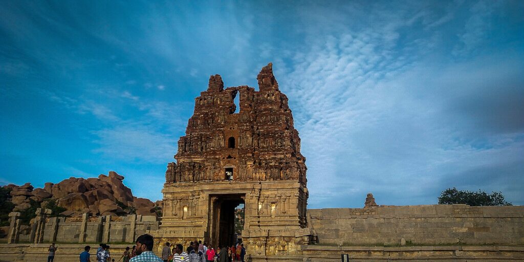 Intricately carved Vittala temple stone chariot against a clear blue sky in Hampi
