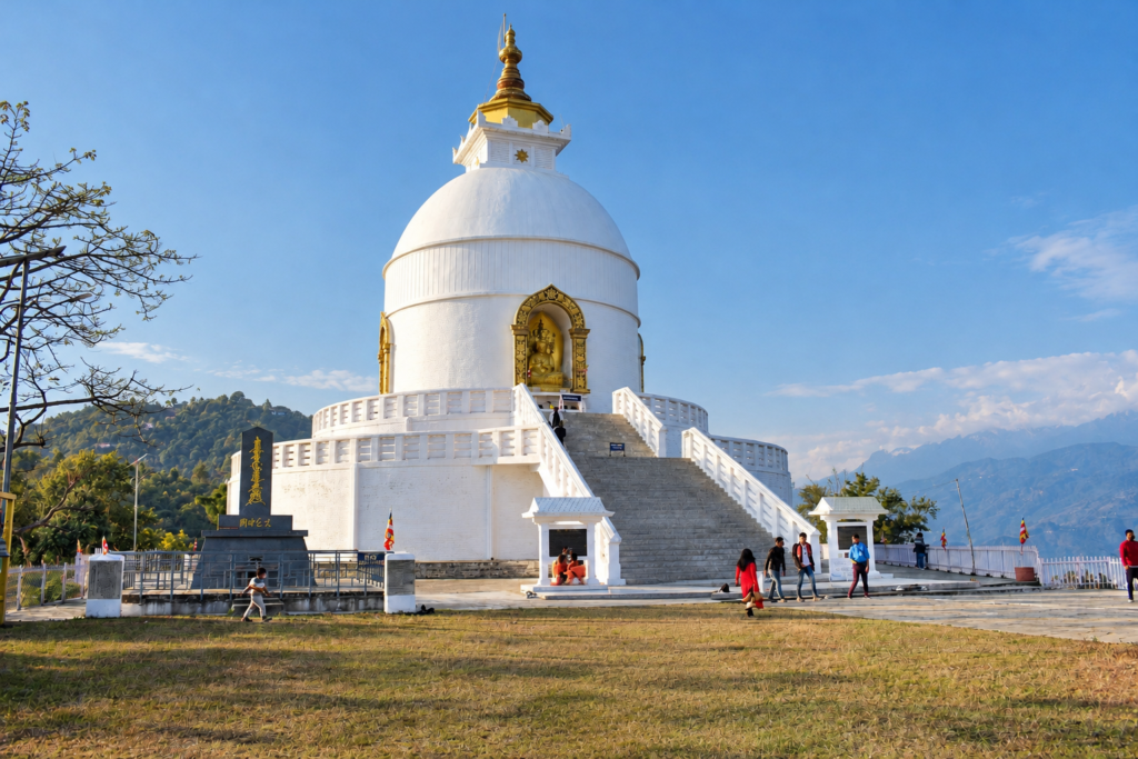 Brilliant white World Peace Pagoda on Ananda Hill in Pokhara overlooking green valleys and distant snow peaks.